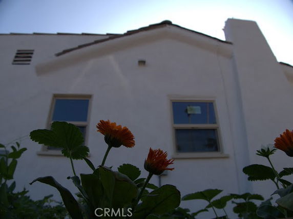 Front view of a two-story house with two windows and a chimney.