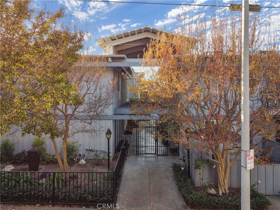 Front view of a multi-story house with a gated entrance and trees surrounding the property.
