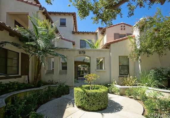 Front view of a multi-story house with arched entryway and surrounding greenery.
