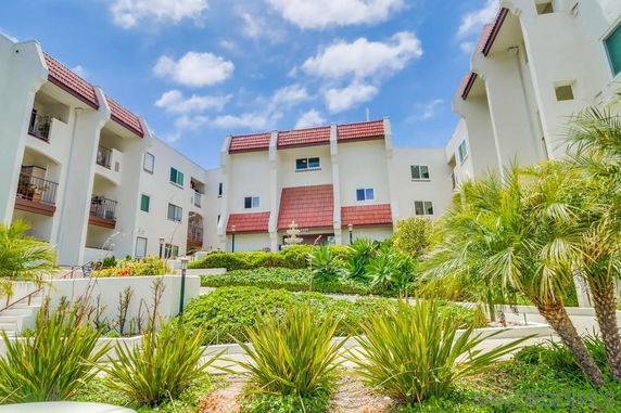 Front view of a multi-story residential building with red-tiled roofs and balconies.