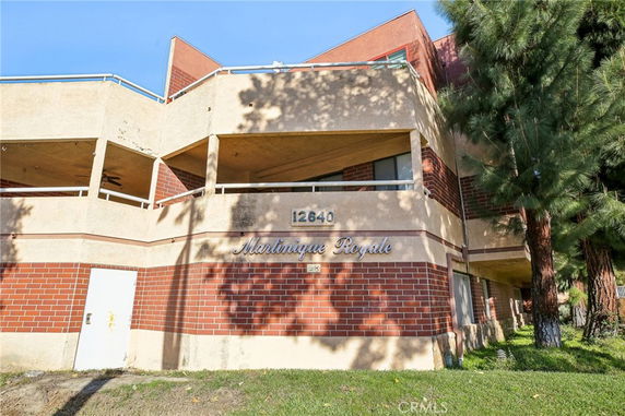 Front view of a multi-story building with balconies and brick exterior.
