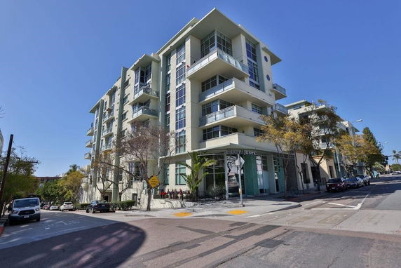 Front view of a multi-story apartment building with balconies and large windows.