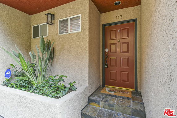 Front entrance of a house with a red door and small porch area.