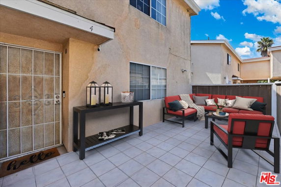Front view of a two-story house with a tiled patio and outdoor seating area.