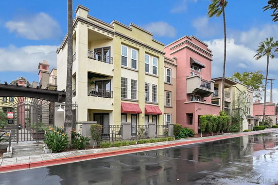 Front view of a three-story apartment building with balconies and red awnings.