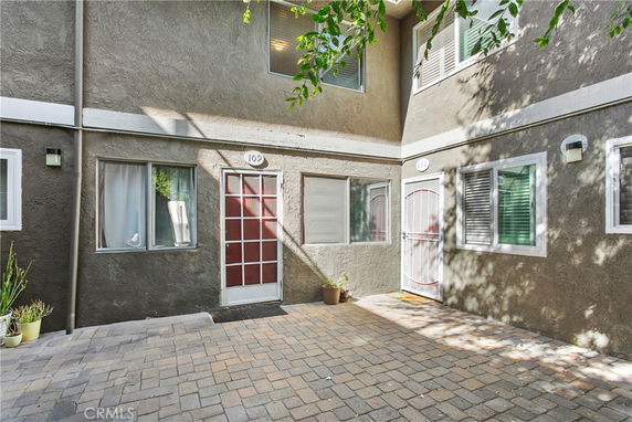Front view of a townhouse with a concrete pathway and multiple windows.