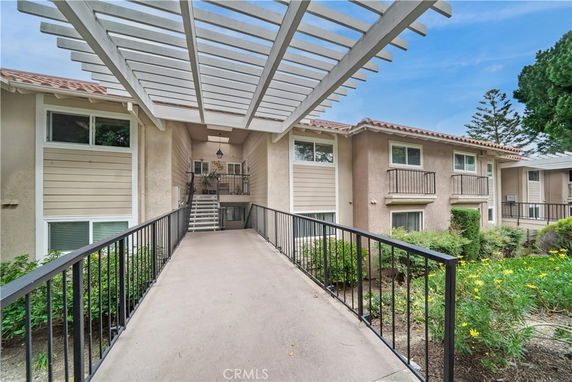 Front view of a house with an overhanging pergola and connecting walkway.