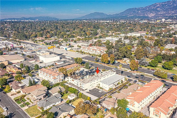 Aerial view of a neighborhood with residential buildings and a highway, surrounded by trees and mountains in the background.