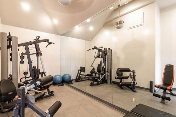 Home gym area with exercise equipment and mirrors on the wall.