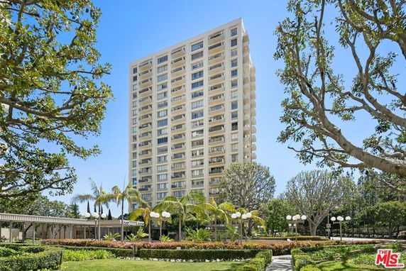 Front view of a tall residential building with multiple balconies.