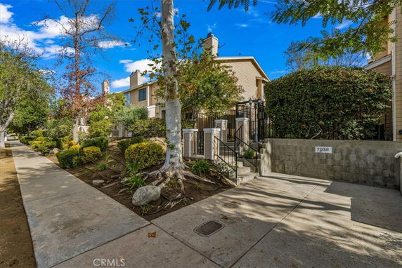 Front view of a multi-story residential building with trees and a pathway.
