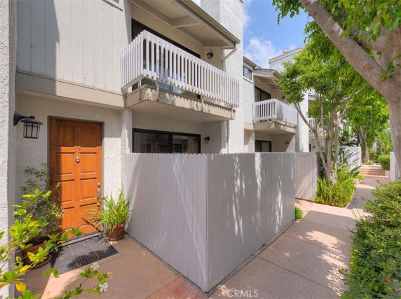 Front view of a multi-level residential building with balconies and a wooden door.