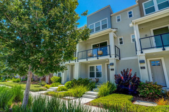 Front view of a multi-story house with balconies and landscaped garden.