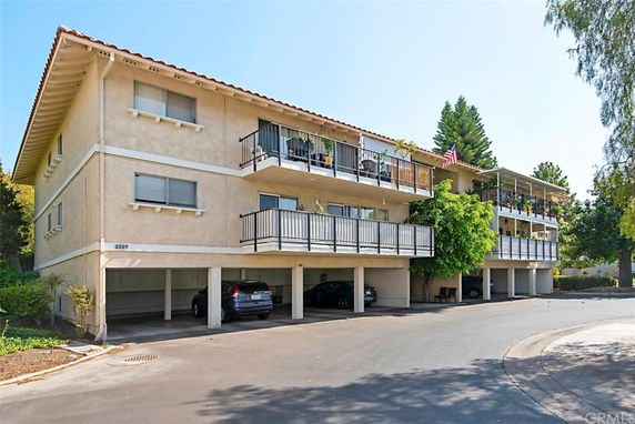 Front view of a two-story apartment building with balconies and covered parking.