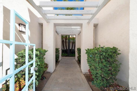 Front view of a building entrance with a pathway and pergola overhead.