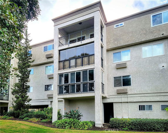 Front view of a multi-story apartment building with balconies and large windows.