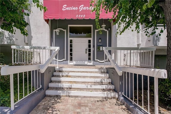 Front view of a building entrance with stairs and a red awning.