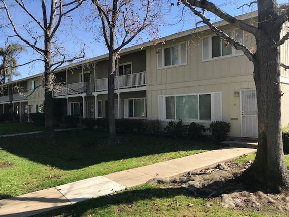 Front view of a two-story apartment building with balconies and white siding.