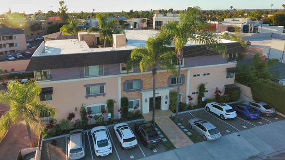 Front view of a multi-story apartment building with a parking area in front.