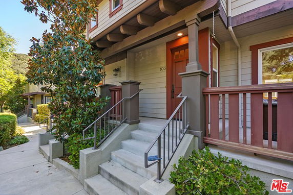 Front view of a two-story house with a wooden porch and steps leading to the entrance.