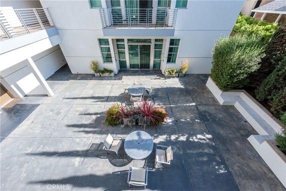 Outdoor view of a building's patio area with seating and plants.
