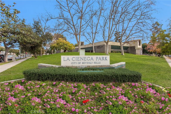 View of La Cienega Park sign surrounded by landscaped greenery and flowers.