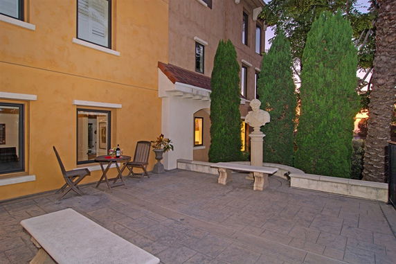 Courtyard view with a bust statue and seating area next to a multi-story building.