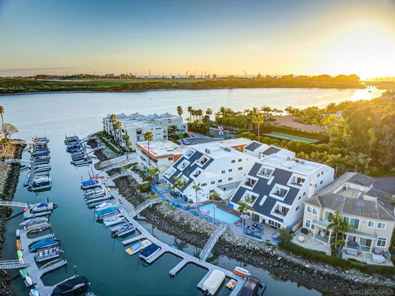 Aerial view of waterfront residential buildings and marina at sunset.