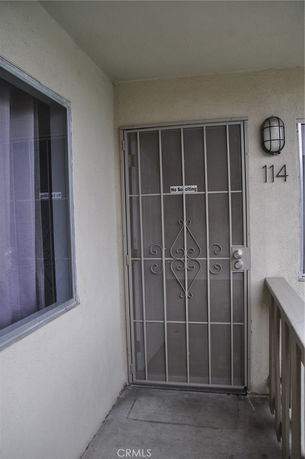 Front entry door with iron security gate and window adjacent to it.