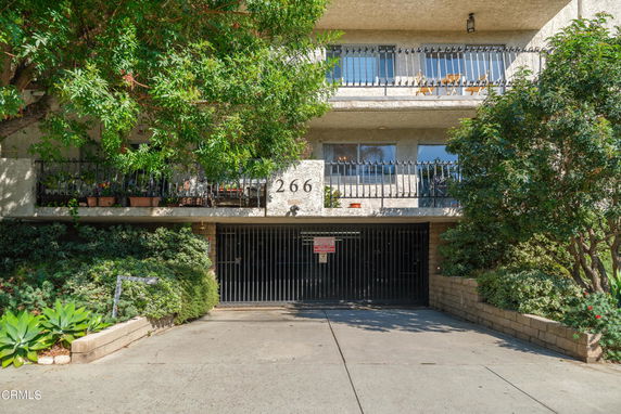 Front view of a multi-story residential building with balconies and gated entry.
