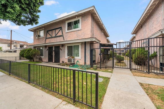 Front view of a two-story residential building with gated entrance and lawn.