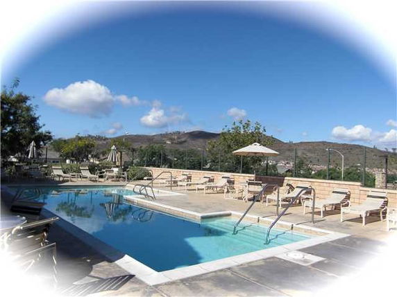 Outdoor swimming pool with lounge chairs and umbrellas.