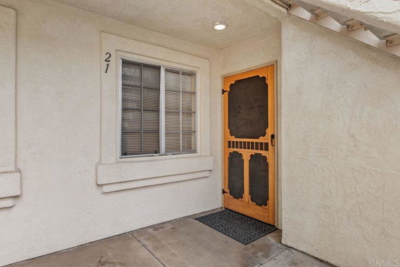 Front view of a building entrance with a wooden screen door and window.