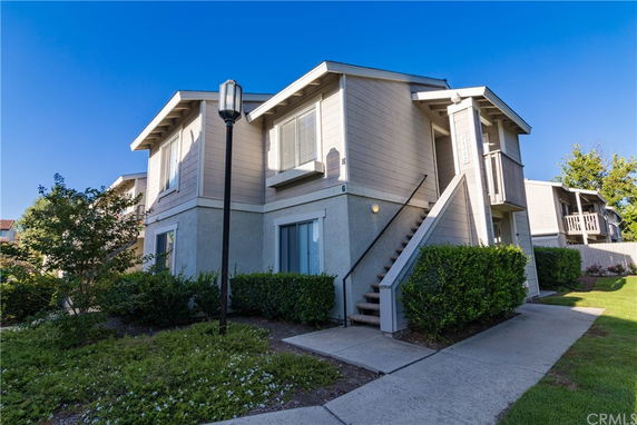 Front view of a two-story house with external stairs and balcony.