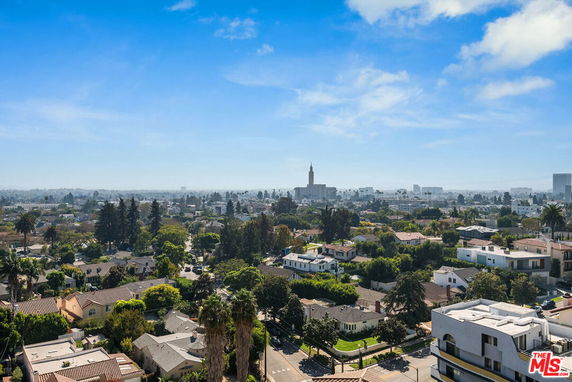 Wide angle view of a cityscape with numerous houses and buildings under a blue sky.