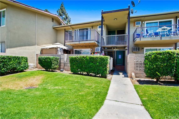 Front view of a two-story residential building with balconies and a pathway leading to the entrance.
