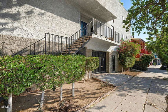 Front view of a two-story building with external staircase and gated entrance.