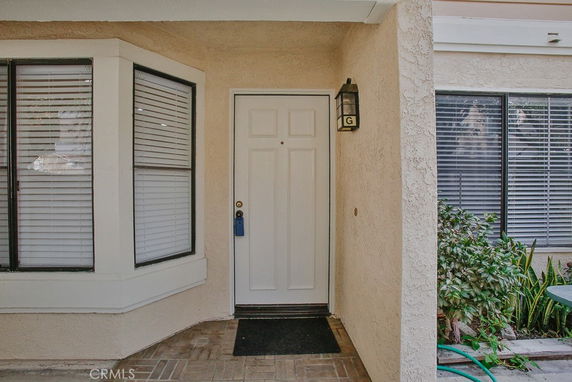 Front view of a house with a white door and large windows with blinds.