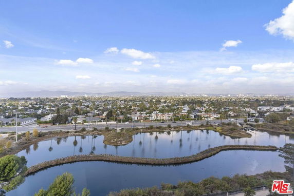 Panoramic view of a neighborhood with houses and a large water body, observed from an elevated position.