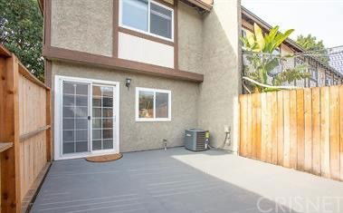 Rear view of a two-story house with a fenced patio area.