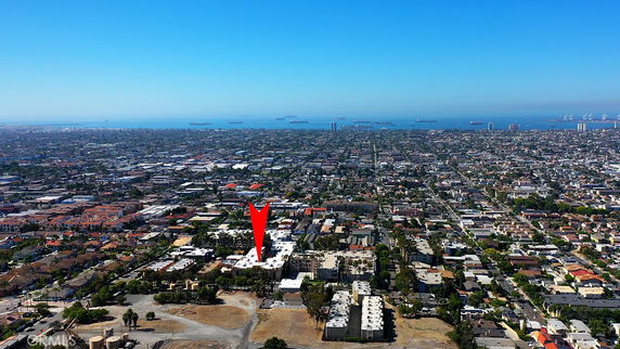 Wide-angle aerial view of a city with numerous buildings and ocean in the background.
