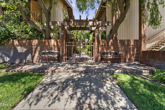 Front view of a residential building with a gated entrance and benches.