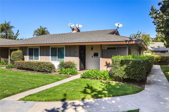 Front view of a single-story house with a sloped roof and multiple satellite dishes.