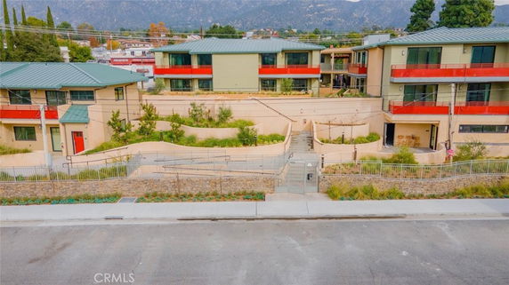 Front view of a multi-story building complex with red accents and green roofs.