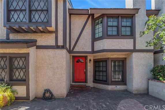 Front view of a two-story house with a distinctive red front door and lattice windows.