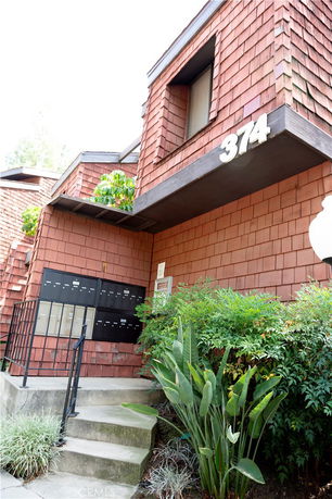 Front view of a multi-story building with a staircase and mailboxes.