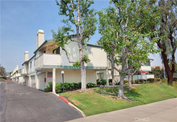 Front view of a multi-story residential building with balconies and trees.