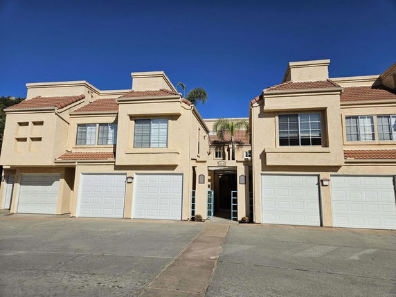 Front view of a two-story house with multiple garage doors and a tiled roof.