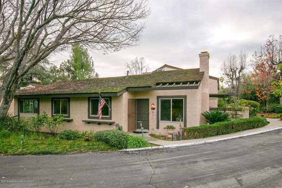 Front view of a single-story house with a chimney and flag.