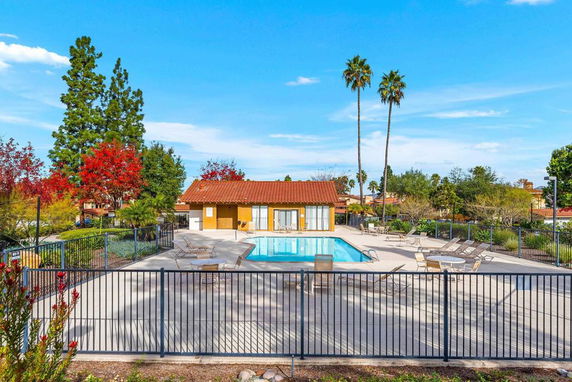Outdoor swimming pool area with surrounding fence and lounge chairs.